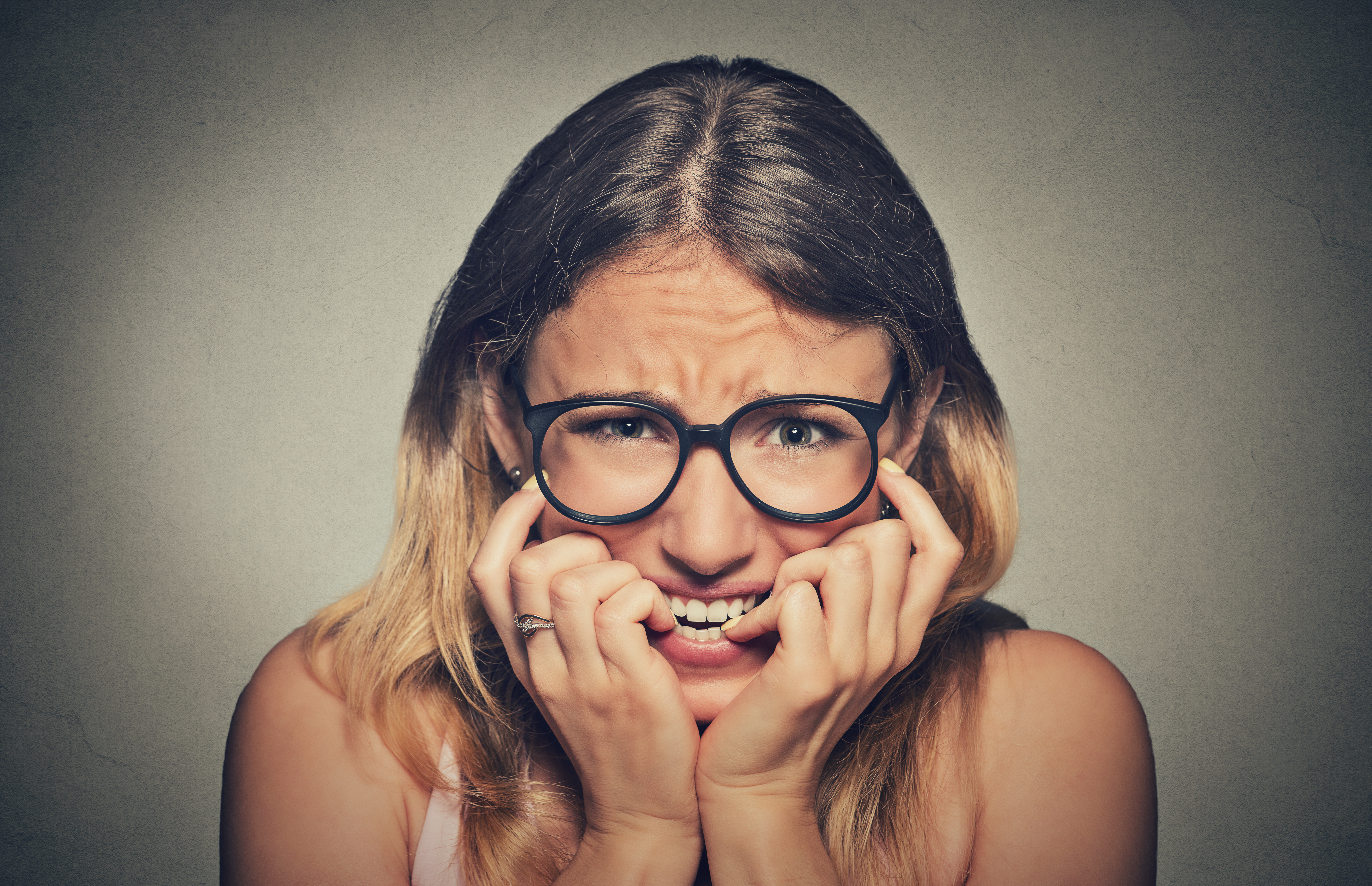 stressed anxious woman in glasses biting fingernails